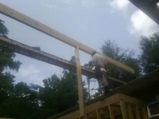 Carpenter setting a ridge beam over a new addition frame — Ice Dam Removal by Roofing Brothers in West Olive