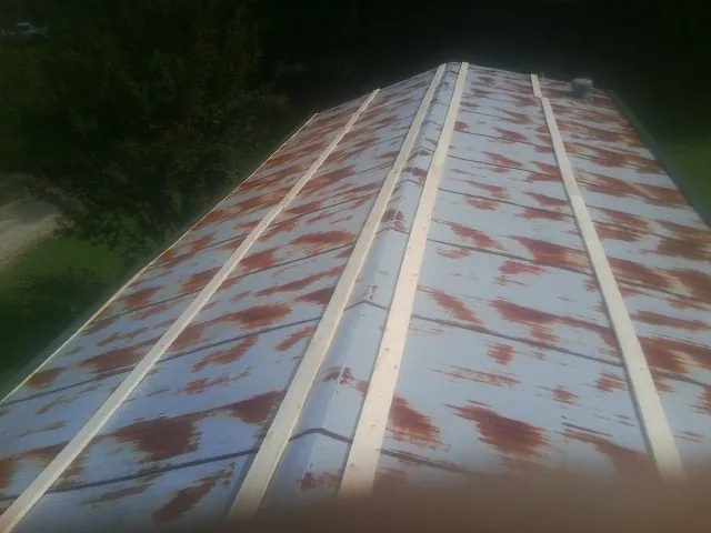 Rusted metal roof panels with new wood purlins before replacement — Storm Damage Roof Repair in West Olive by Roofing Brothers