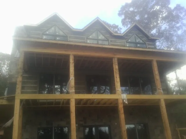 Dormers and porch framing on a large log home under construction — Roof Coating work by our crew in West Olive