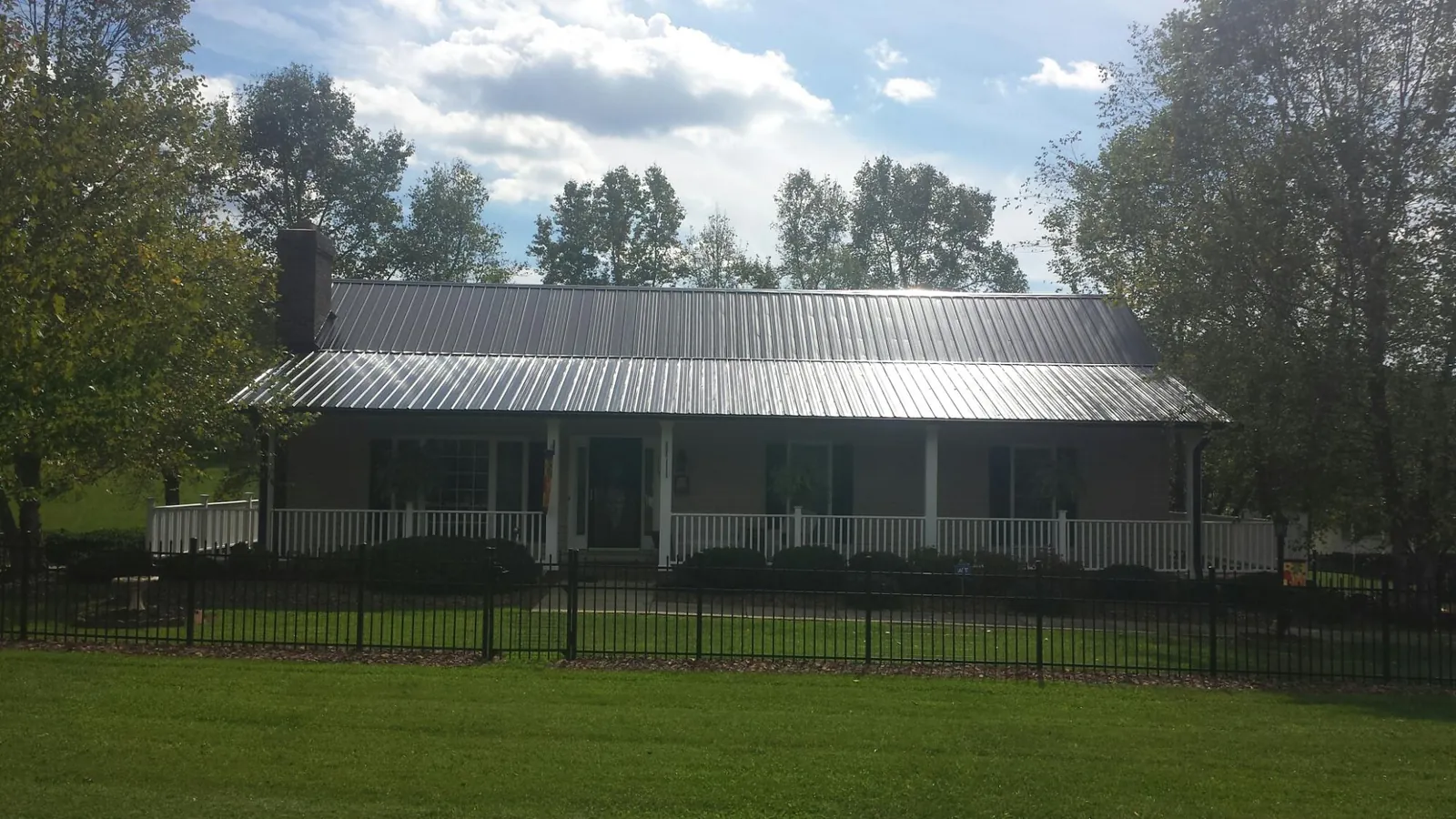 Gray metal roof on a brick ranch with a full width front porch — Gutter Guard Installation work by our crew in West Olive
