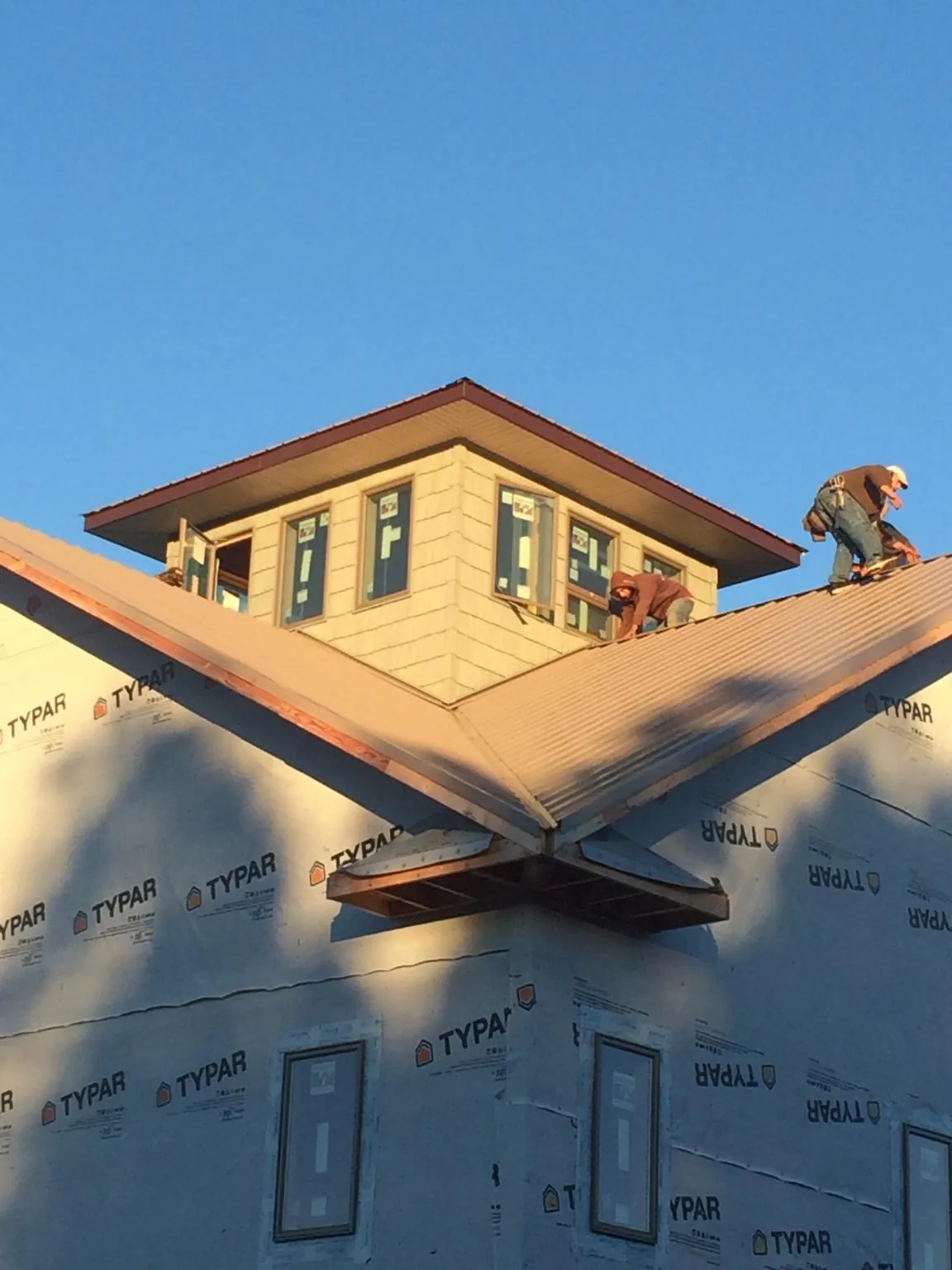 Roofers working around a rooftop cupola on a new metal roof at sunset — Roof Waterproofing in West Olive by Roofing Brothers